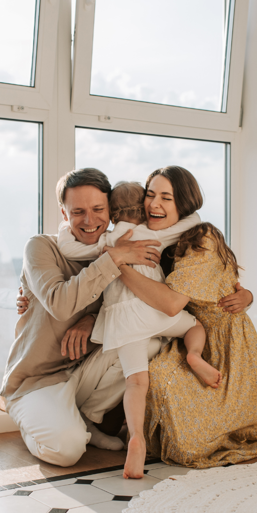 a young child hugging her smiling parents