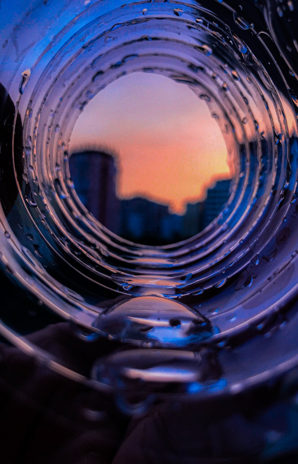 a view of a skyline in the setting sun through a looking glass