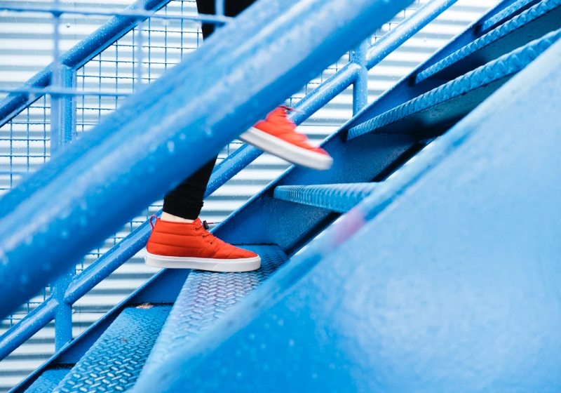 Red shoes going up a flight of metal stairs.