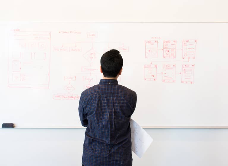 The back of a person looking at a site architecture diagram on a board.