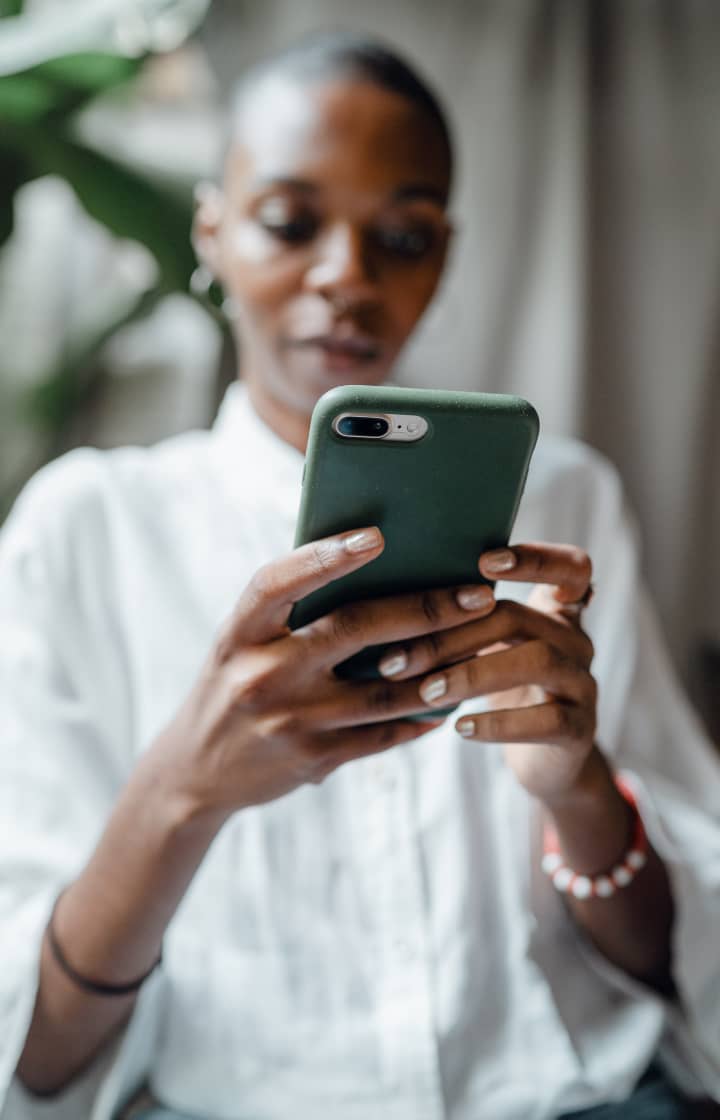 A patient holding a green smartphone, looks at the phone.