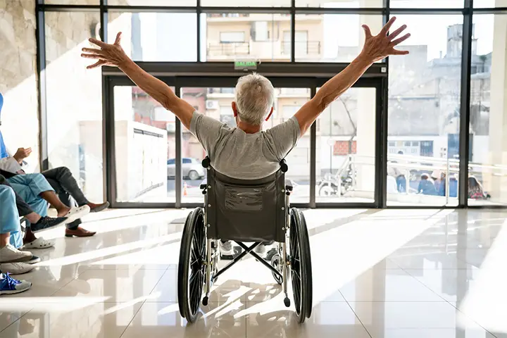 an elderly man leaving the hospital happy in a wheelchair