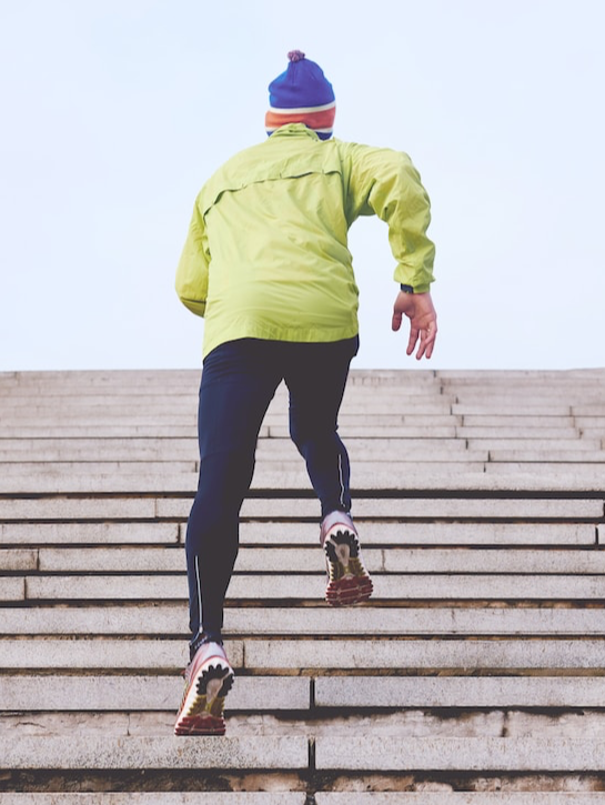 A person wearing athletic gear runs up a large set of stairs.