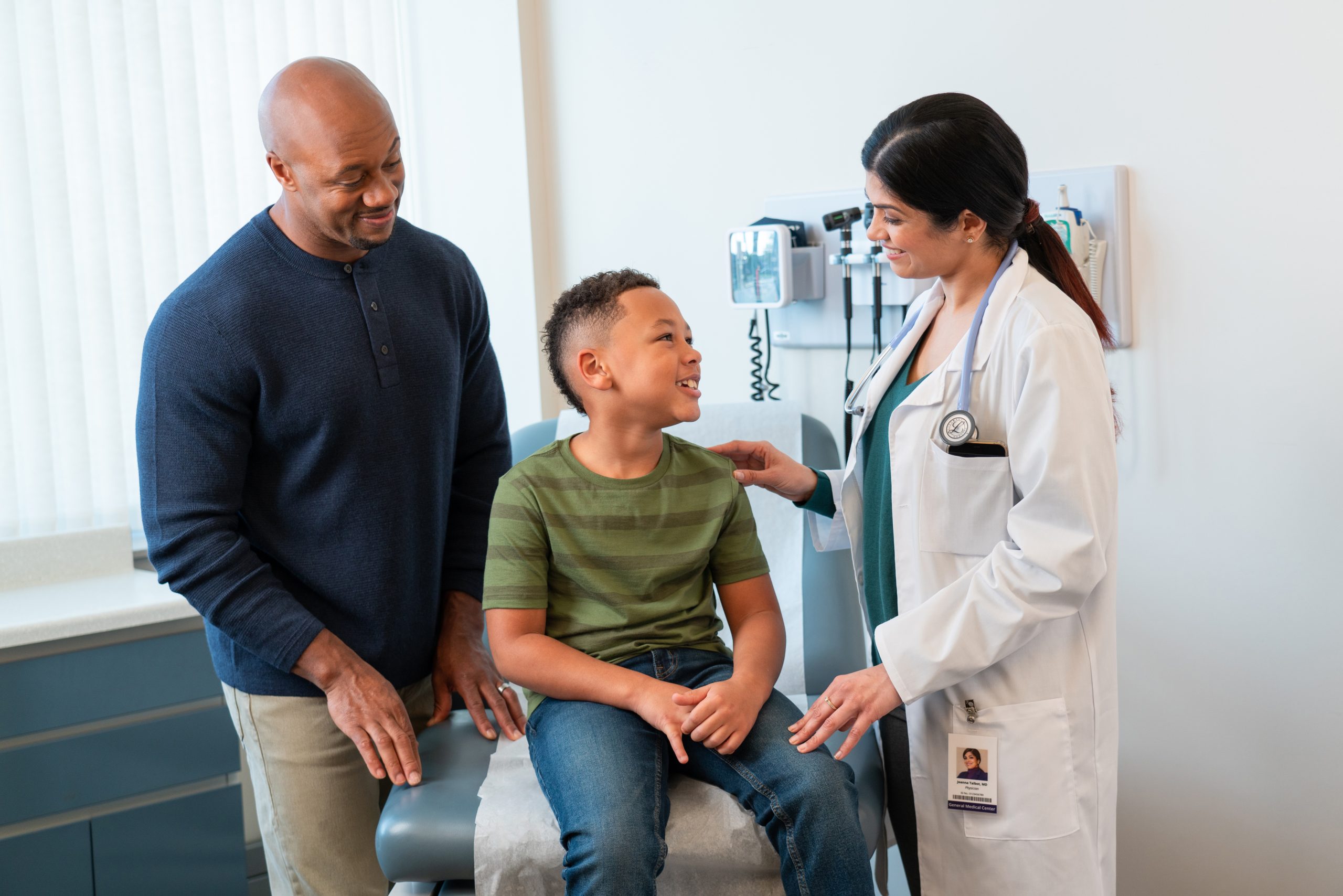 a young boy with his father speaking to a female doctor