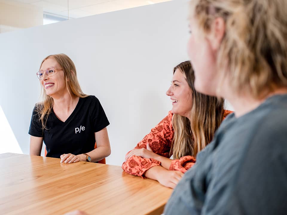 P/E team members smile in a brightly lit conference room in our Chicago office.