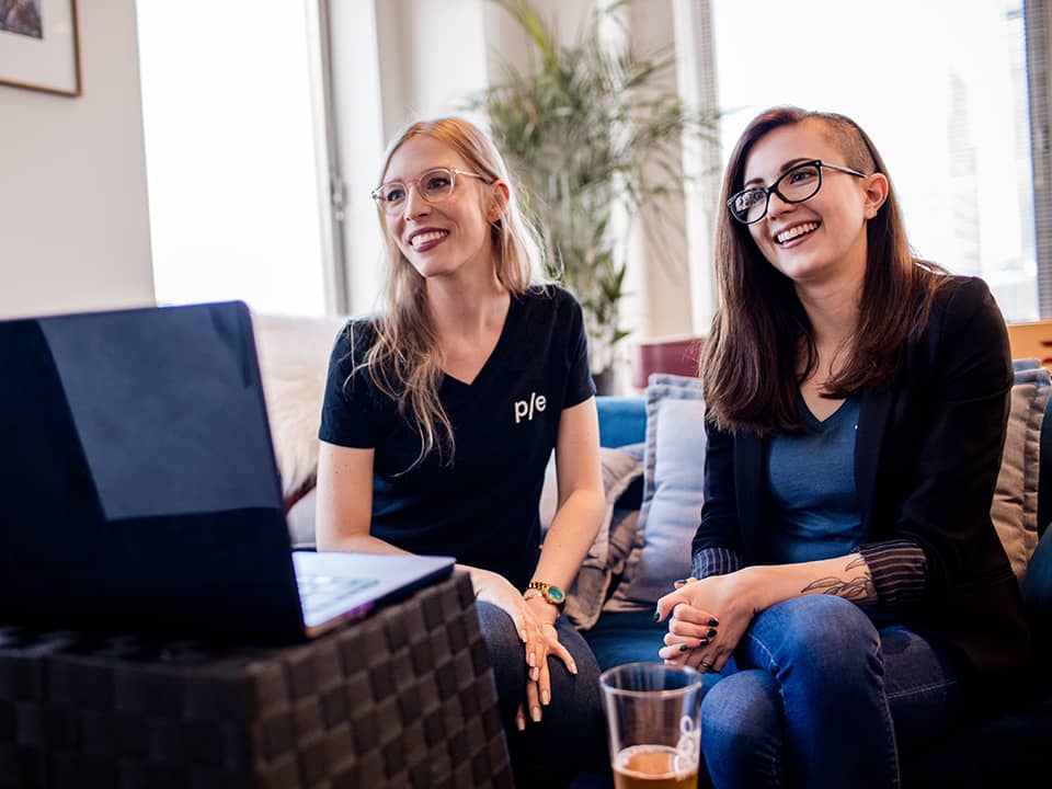 Two P/E employees smile during a meeting.