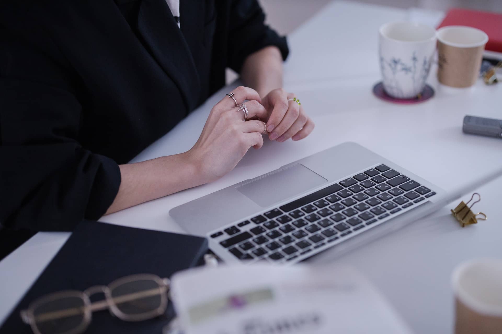 Stock image of a person sitting at a desk with an Apple laptop in front of them.