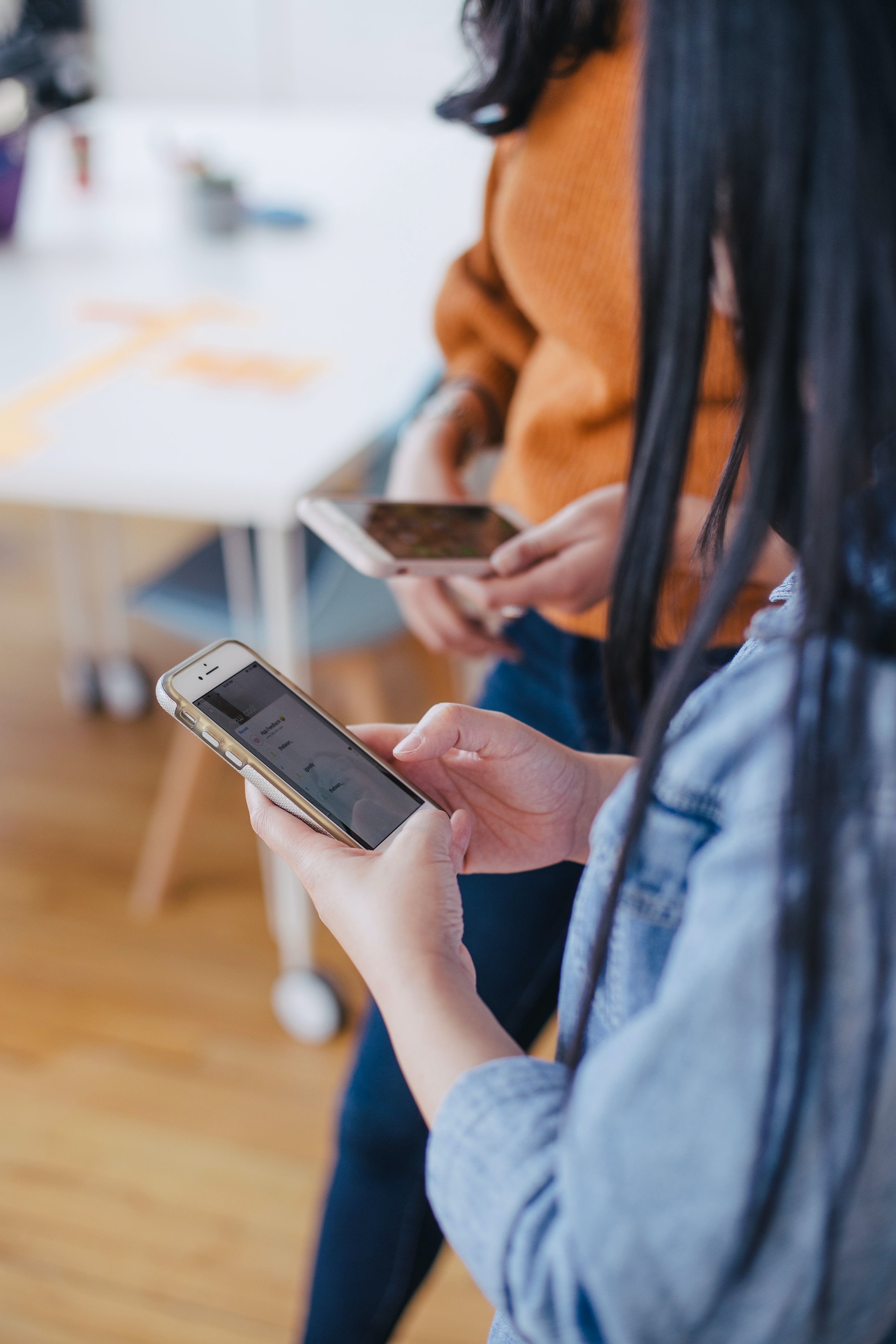 Stock image of two individuals on their phone.