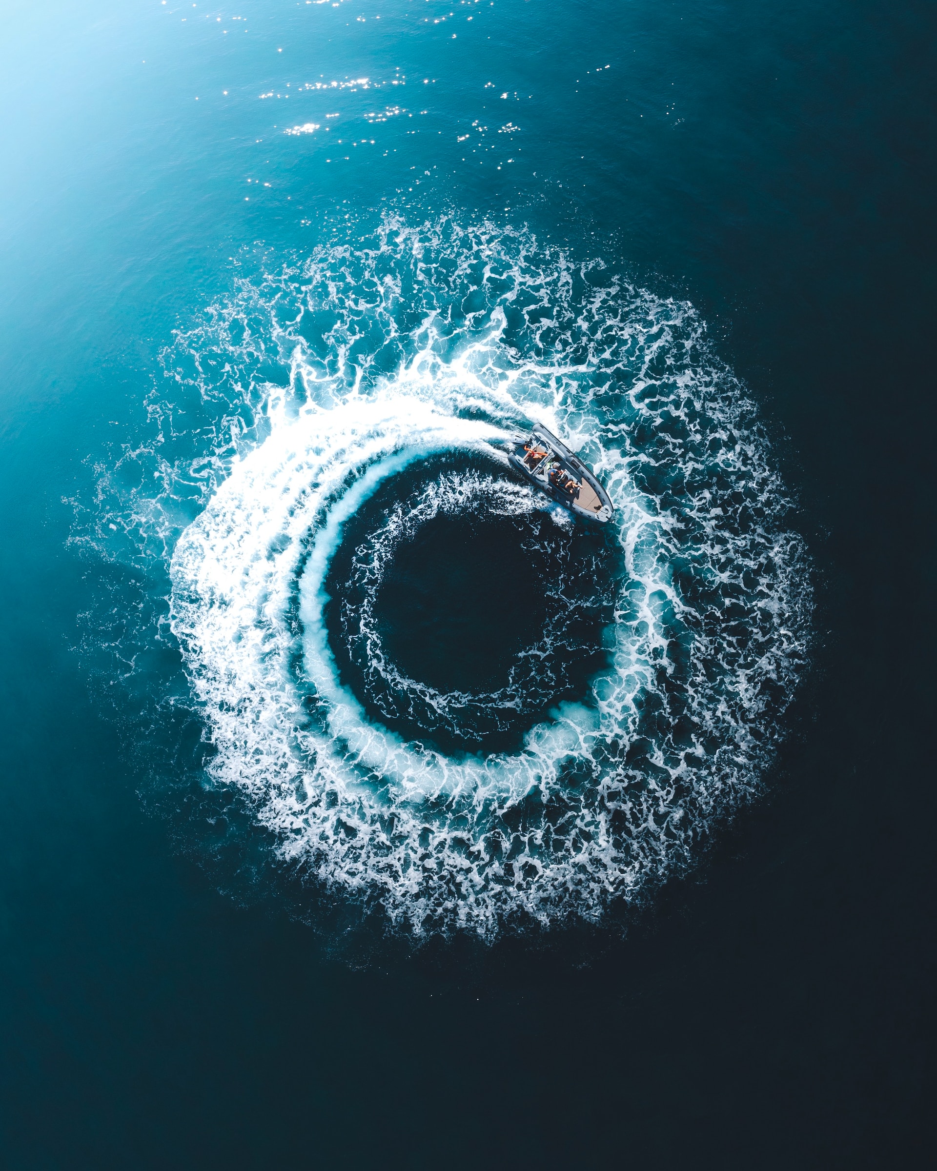 Overhead view looking down at a boat going in a circle with a wake that resembles the iris of an eye.