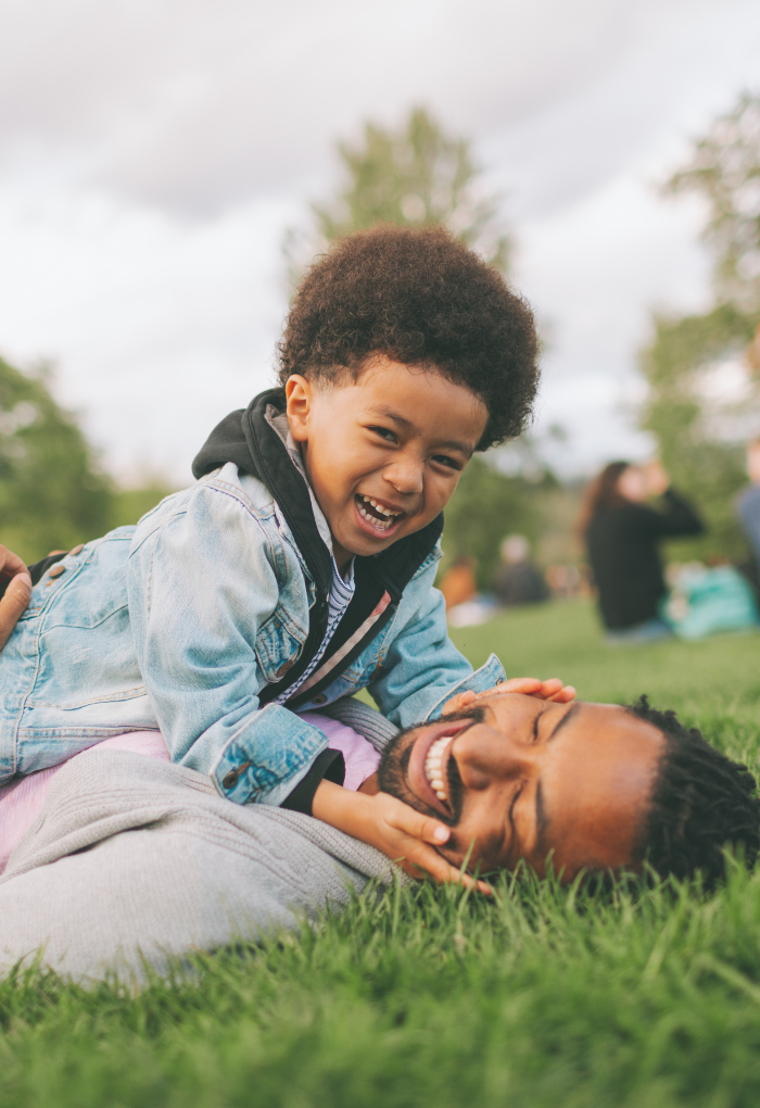 young boy playing with his father in the grass